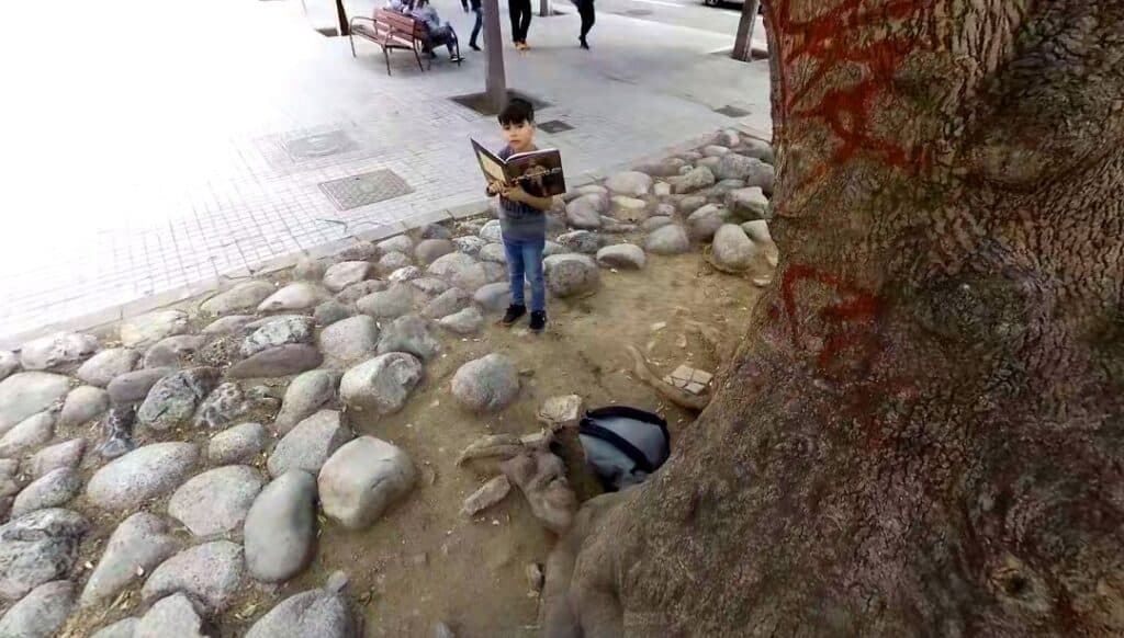 Niño leyendo en la calle mientras es acosado. Assetjament escolar.